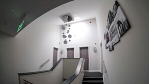 A modern interior with a curved staircase, a wall-mounted light fixture, and a poster of a cityscape. - Anelli Hotel (Southport)