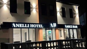 The exterior of Anelli Hotel and Amici Bar at night, featuring illuminated signage and a black balustrade. - Anelli Hotel (Southport)