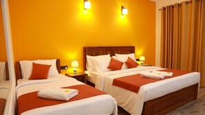 Ein Hotelzimmer mit zwei Betten, jeweils mit weißer Bettwäsche und orangenen Akzenten, Holz-Kopfteilen, Nachttischlampen und einem Holzboden.