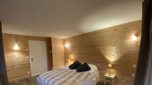 A bedroom with a bed, bedside tables, and wooden walls. - Family Chalet for 8/9, 5 mins to Village Center, Mountain Views, WiFi (Arêches-Beaufort)