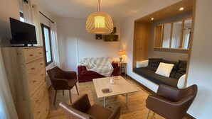 A modern living room with a sofa, chairs, a TV, a lamp, and a wooden ceiling. - Family Chalet for 8/9, 5 mins to Village Center, Mountain Views, WiFi (Arêches-Beaufort)