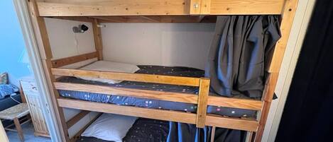 A bunk bed with three levels, wooden construction, and a simple, utilitarian design.