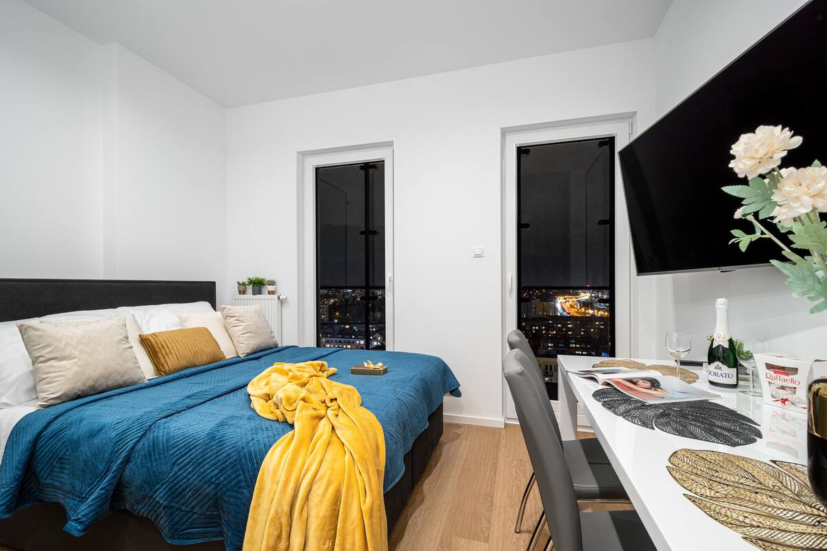 Een moderne hotelkamer met een bed, een eettafel en uitzicht op de stad.