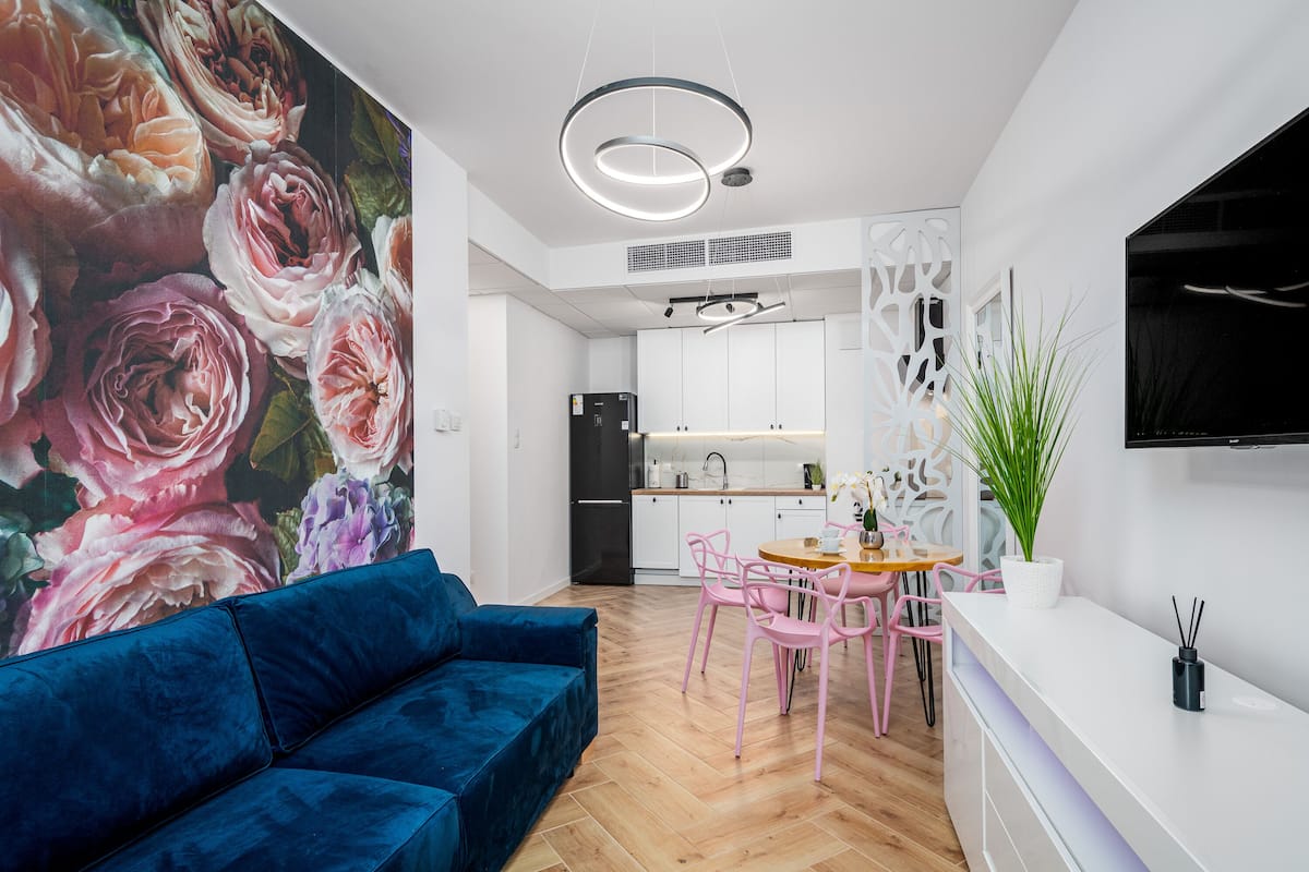 Een moderne keuken met witte kastjes, een zwarte koelkast en een eethoek met roze stoelen.