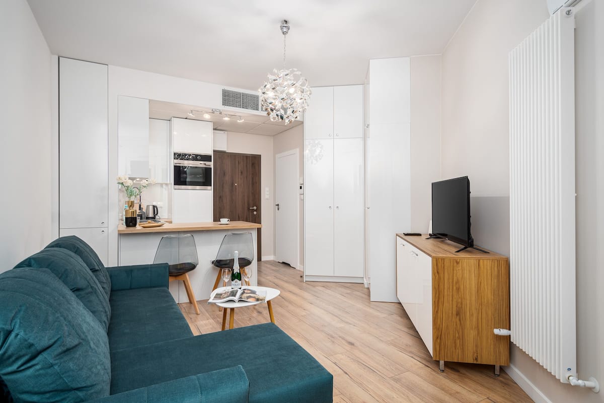 Een moderne woonkamer met een blauwgroene bank, een houten salontafel en een televisie op een houten kast.