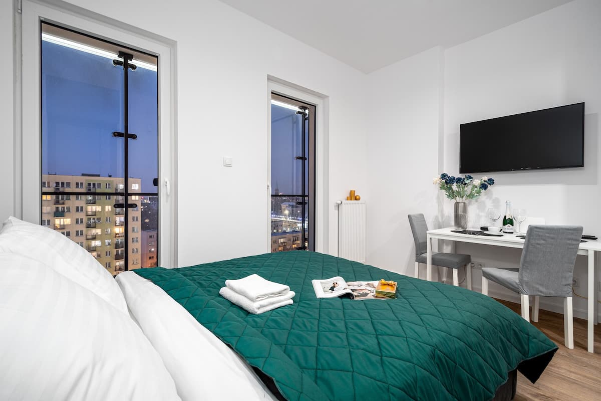 Een moderne hotelkamer met een groot bed, een bureau met stoel, en een televisie aan de muur.