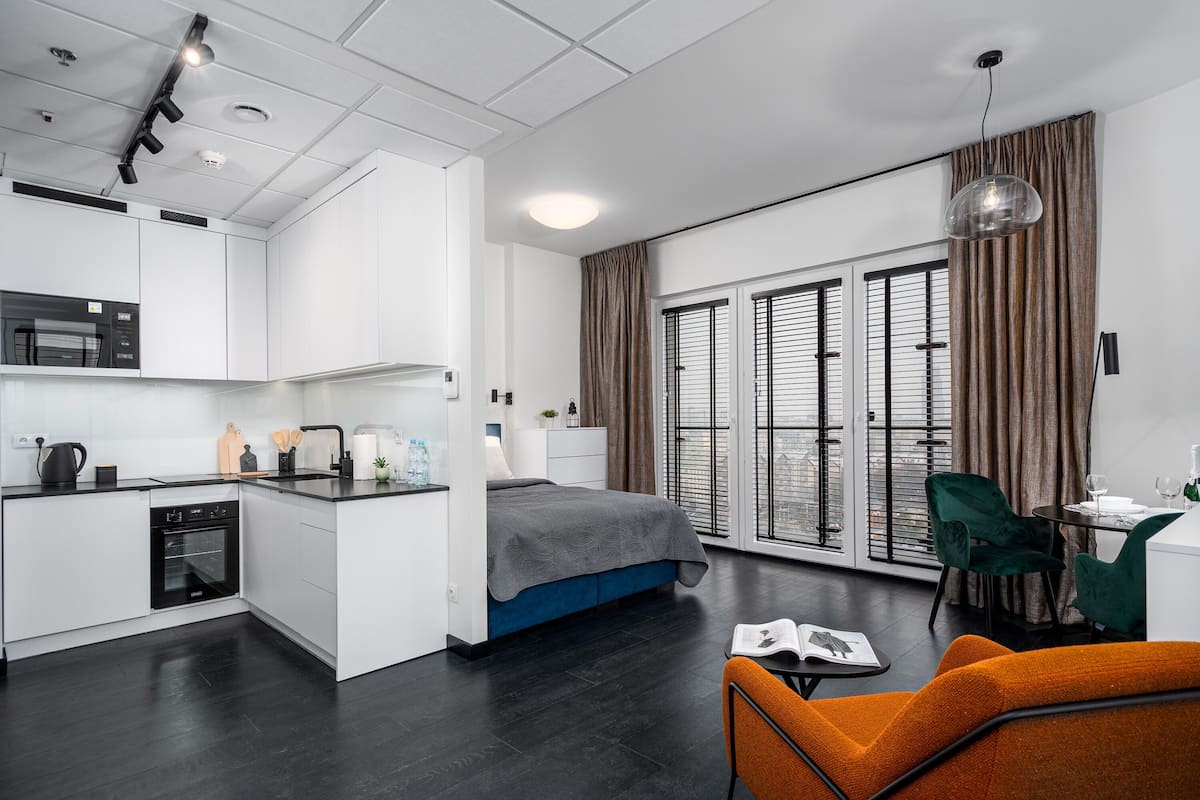 Een modern appartement met kitchenette, een slaapkamer met groot raam en een eethoek.