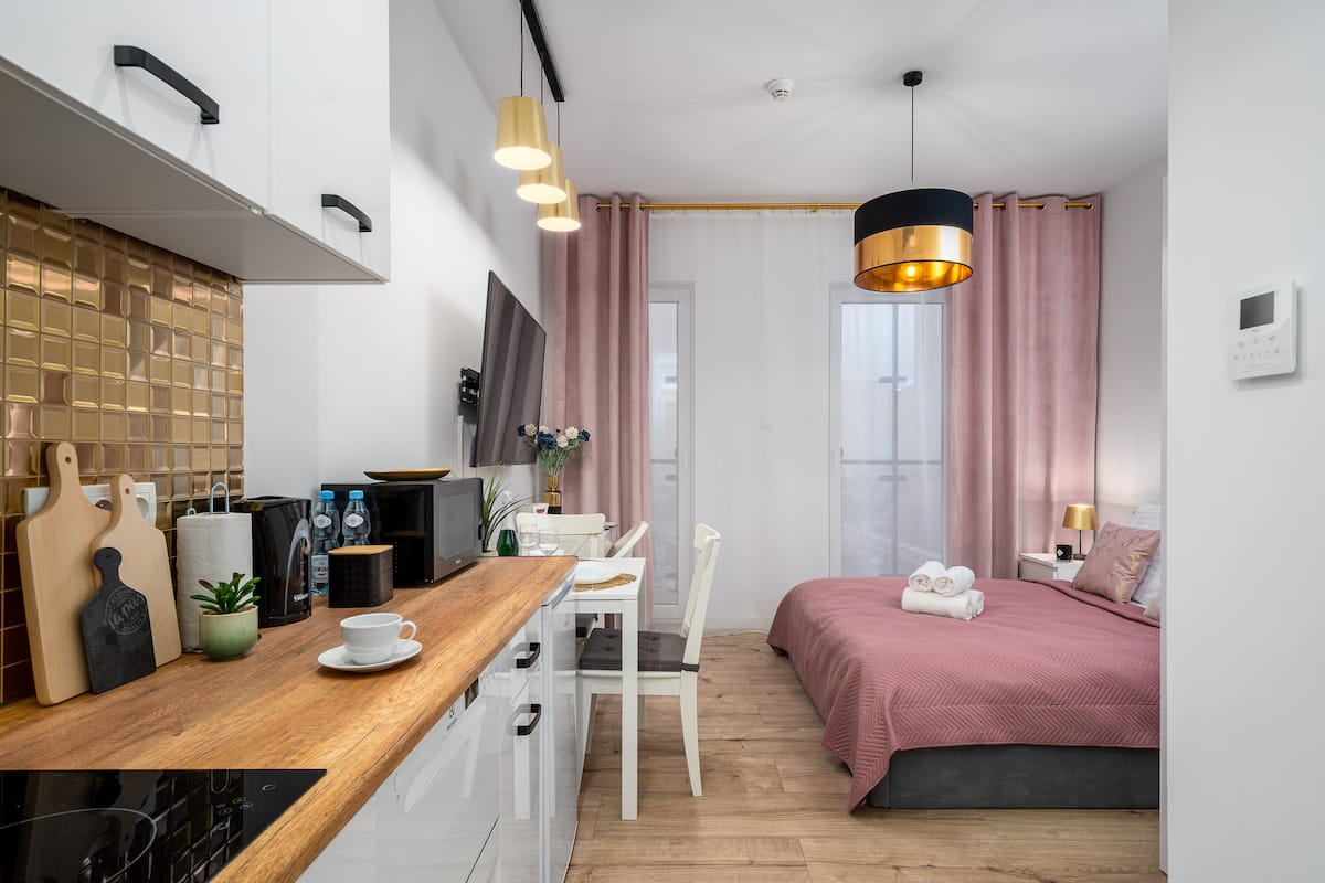 Een kleine slaapkamer met een bed, nachtkastje en een bureau met stoel.
