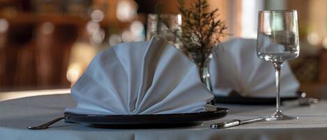 Una mesa dispuesta con un mantel doblado, una copa de vino y un tenedor.