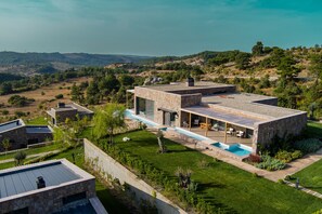 A modern house with a swimming pool, stone exterior, and a view of the surrounding landscape. - Cabras Kazdağları (Ayvacik)