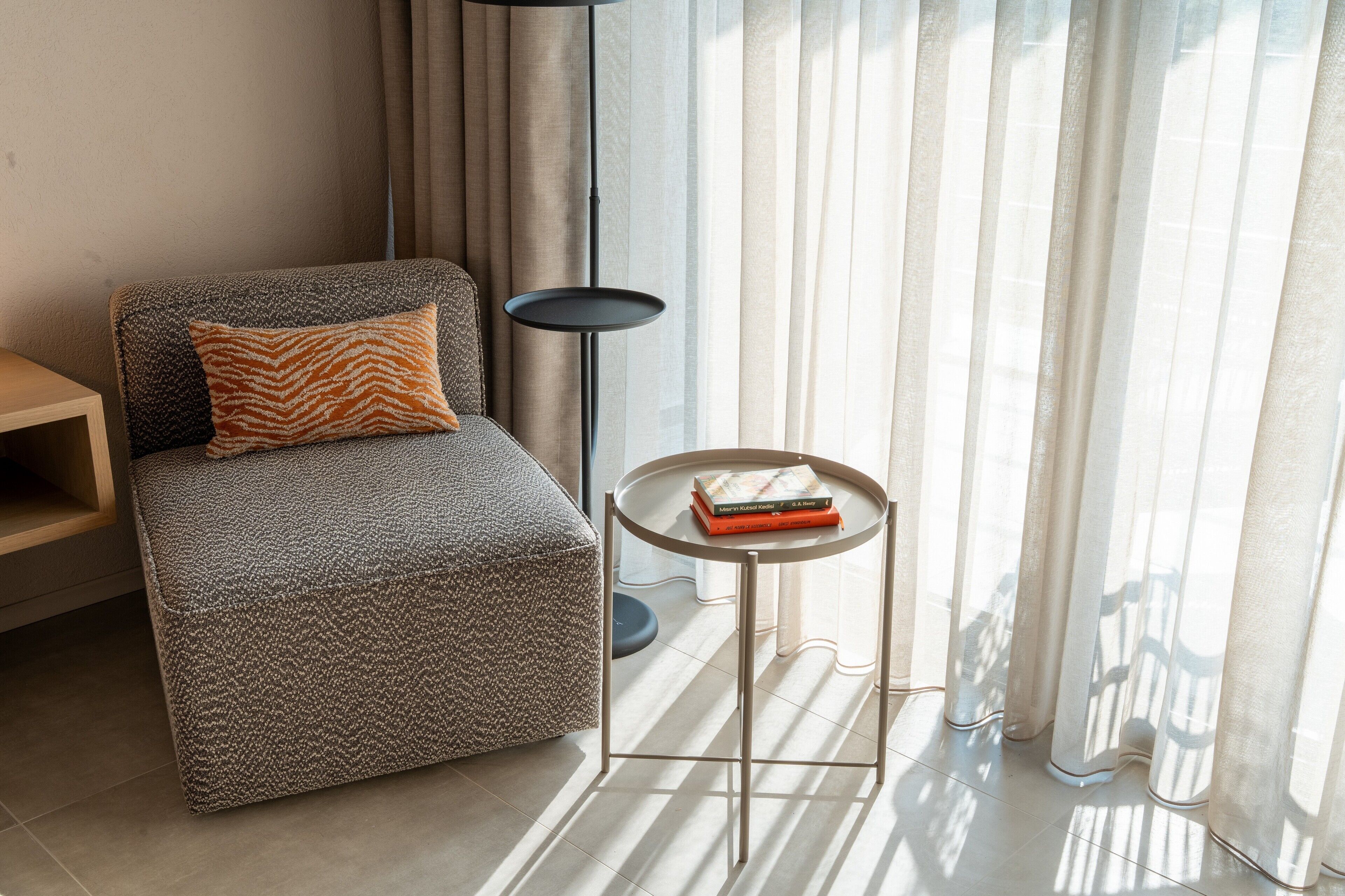 A modern living room with a sofa, a small round table with a book, and a floor lamp.