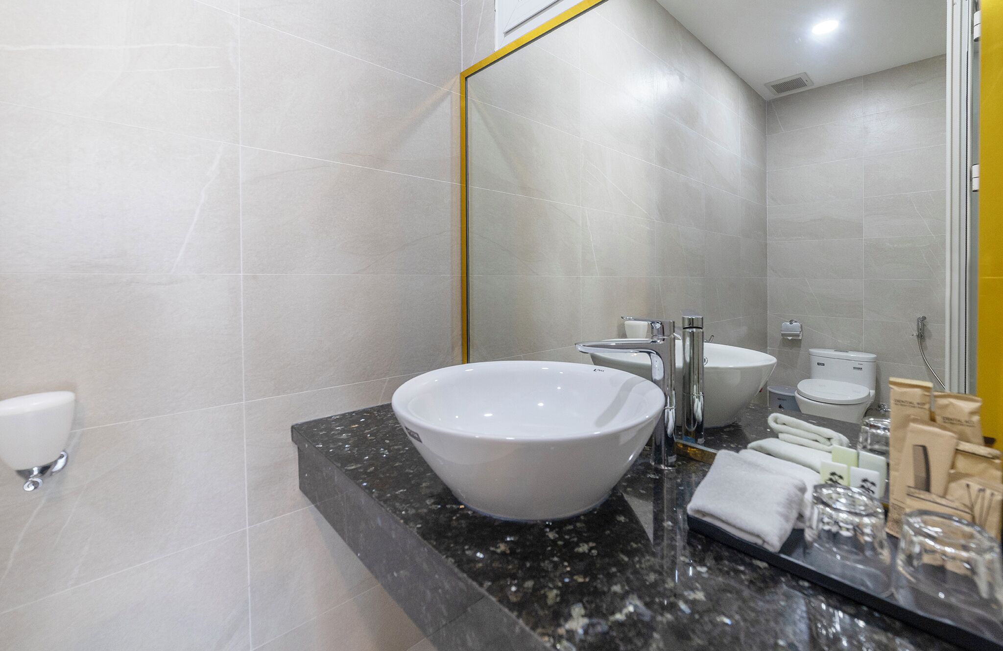 A modern bathroom with a large white sink, a mirror with a gold frame, and a toilet.