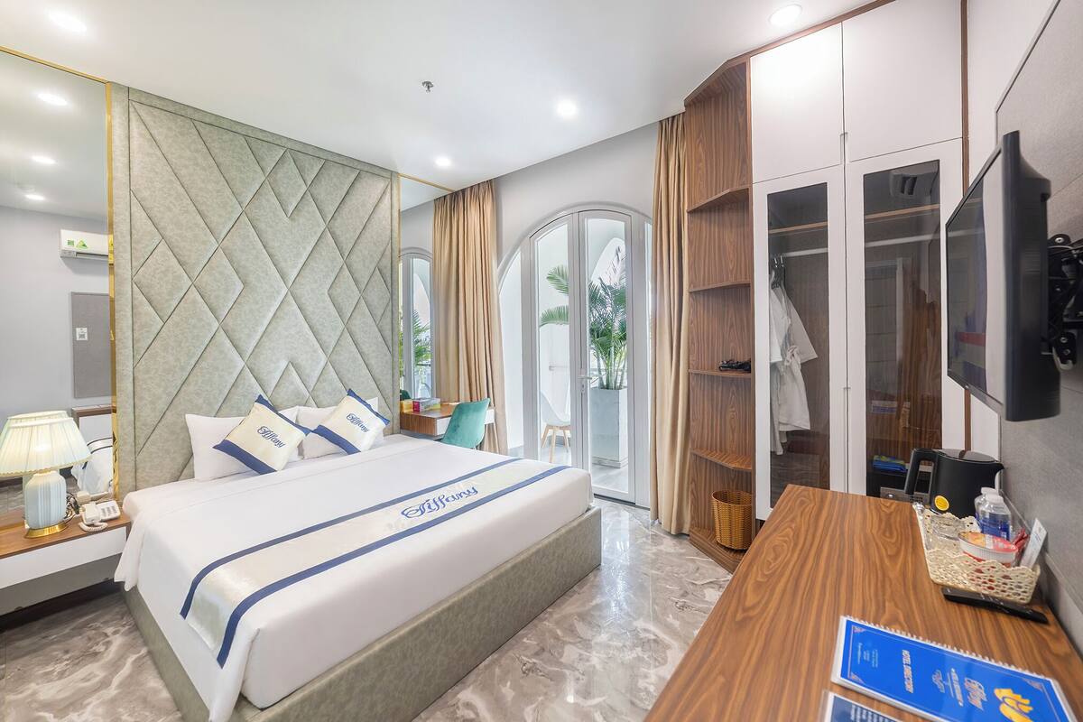 Una habitación de hotel con cama, escritorio, televisor y armario.