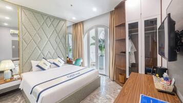 A hotel room with a bed, a desk, a TV, and a wardrobe.