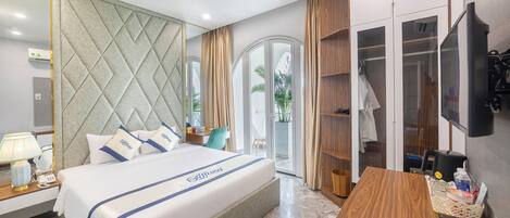 Una habitación de hotel con cama, escritorio, televisor y armario.