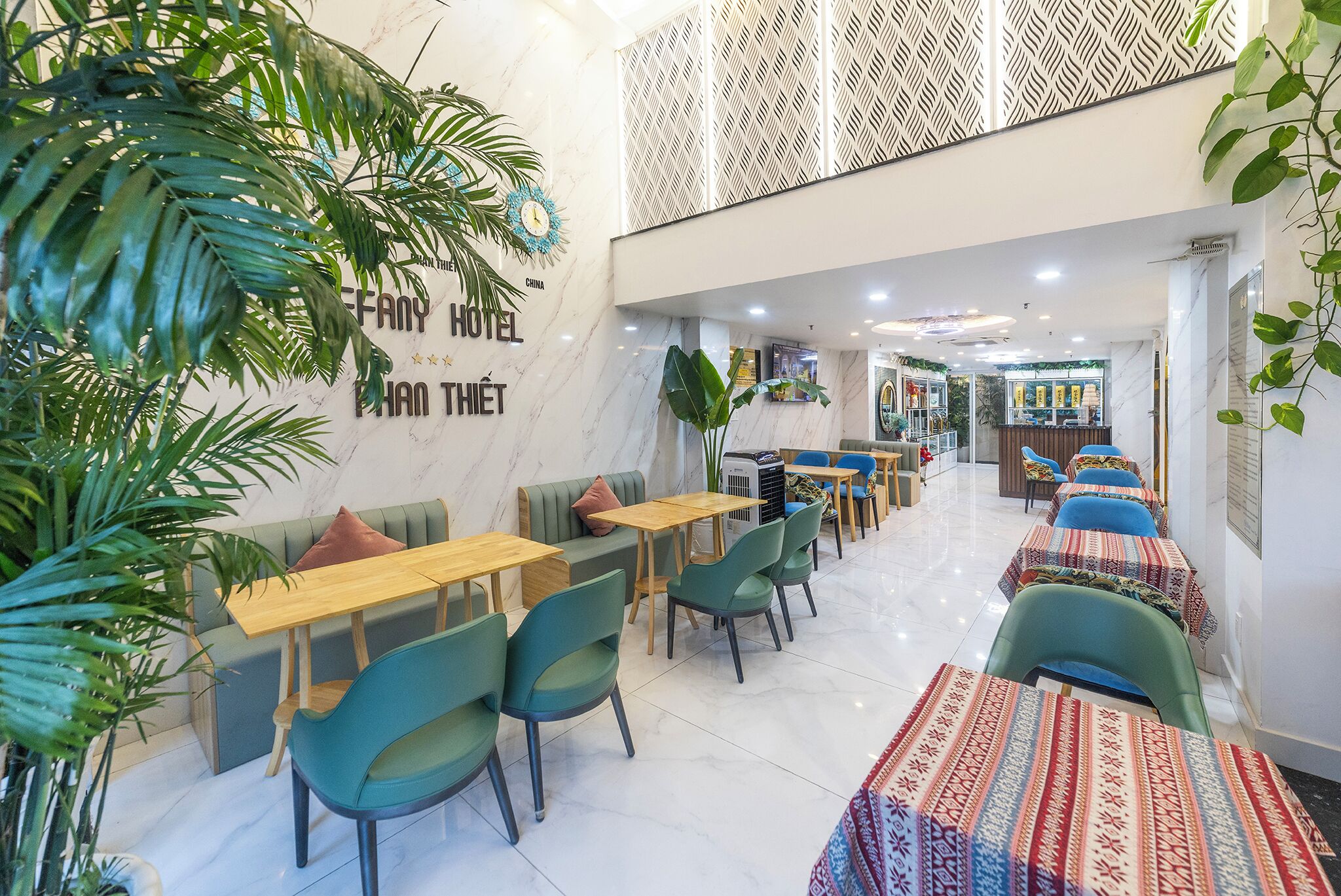 A hotel lobby with seating areas, a reception desk, and a patterned wall.
