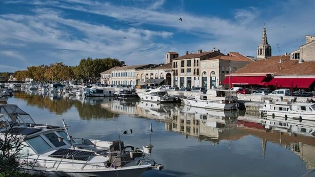 A marina with boats docked, a church spire, and buildings with arched windows. - Beaucaire Cocoon 1 /quais/cité Médiévale/nature (Beaucaire)