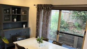A dining area with a table and chairs, a cabinet with glass doors, and a view of a backyard through a sliding glass door. - Berghofen ..Tamborine Mountain Family escape including your furry friends! (Tamborine Mountain)