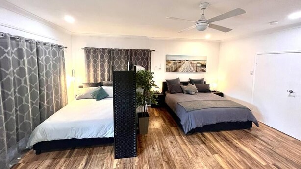 A bedroom with two beds, a ceiling fan, and a large window. - Berghofen ..Tamborine Mountain Family escape including your furry friends! (Tamborine Mountain)