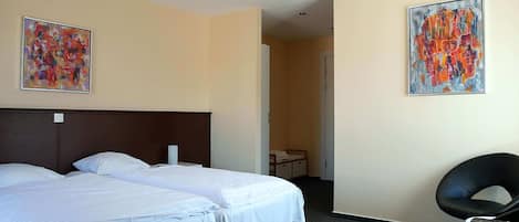 A hotel room with two beds, a desk, and two paintings on the walls.