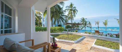 A hotel room with a view of the beach and palm trees.