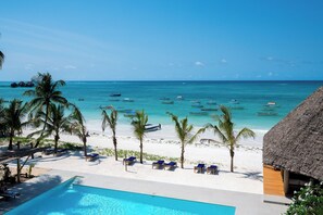 A beach resort with a pool, palm trees, and boats on the water. - Ocean Boutique Hotel (Dongwe)