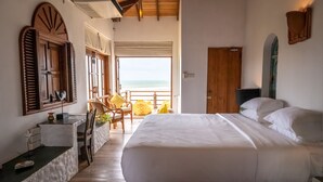 A bedroom with a large bed, a wooden door, and a view of the beach. - Sānti Beach House  (Weligama)