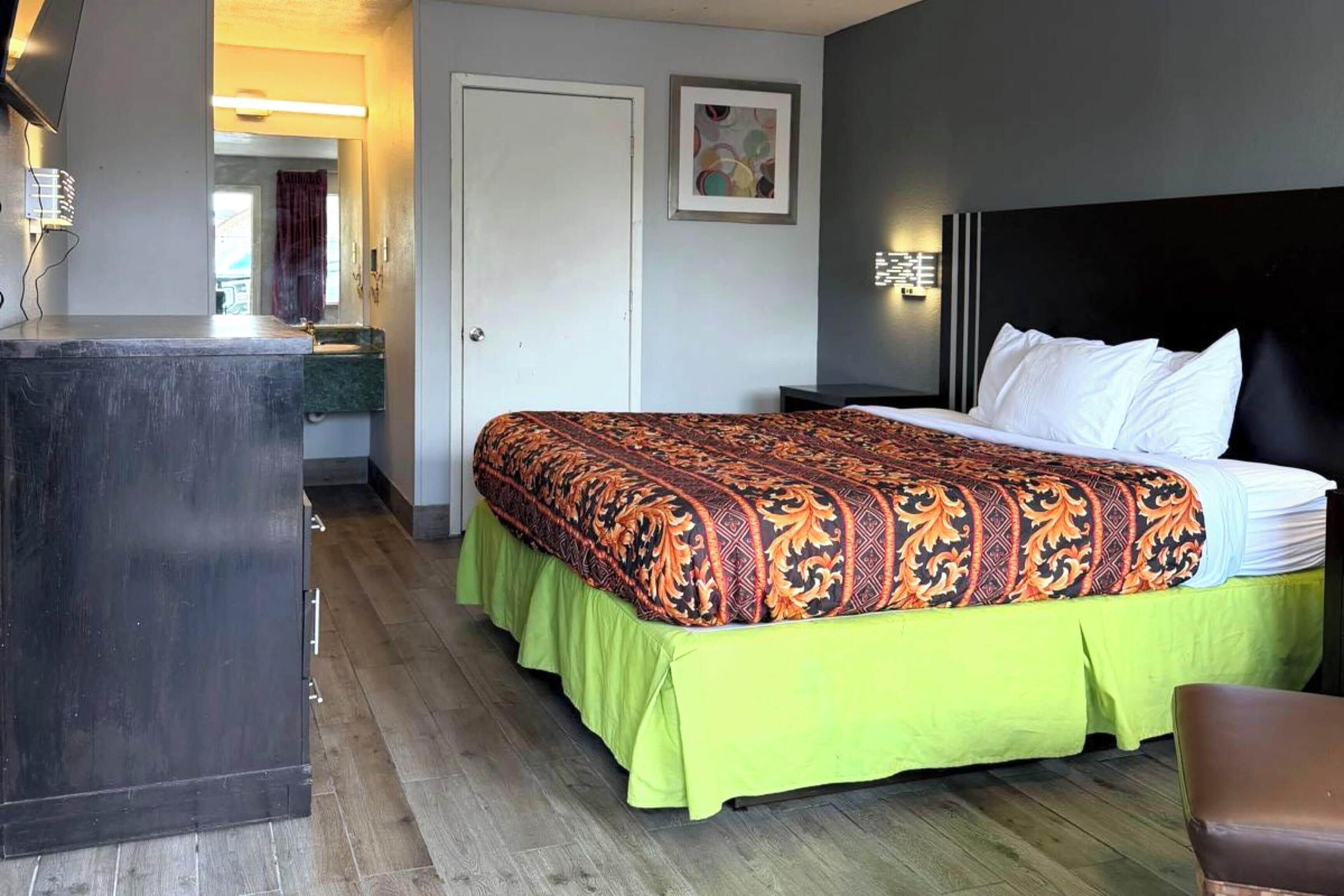 Una habitación de hotel con cama, escritorio, espejo y puerta.