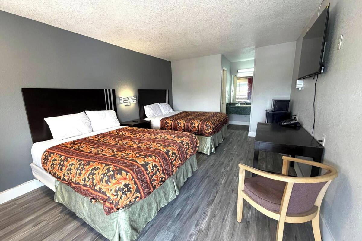 Ett hotellrum med två sängar, ett skrivbord, en stol och en tv.