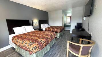 Ett hotellrum med två sängar, ett skrivbord, en stol och en tv.