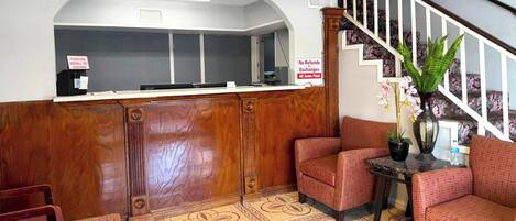 A reception area with a wooden counter, a staircase, and seating with a patterned floor.
