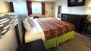 A hotel room with a bed, a television, a desk, and a window with curtains. - Regency Inn Three Rivers I-37 (Three Rivers)