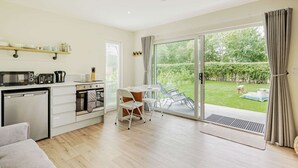 Una cocina moderna con comedor, puerta corrediza de vidrio a un jardín y un sofá en la sala de estar.