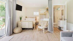 Un dormitorio con cama, mesita de noche, lámpara y vistas al exterior.