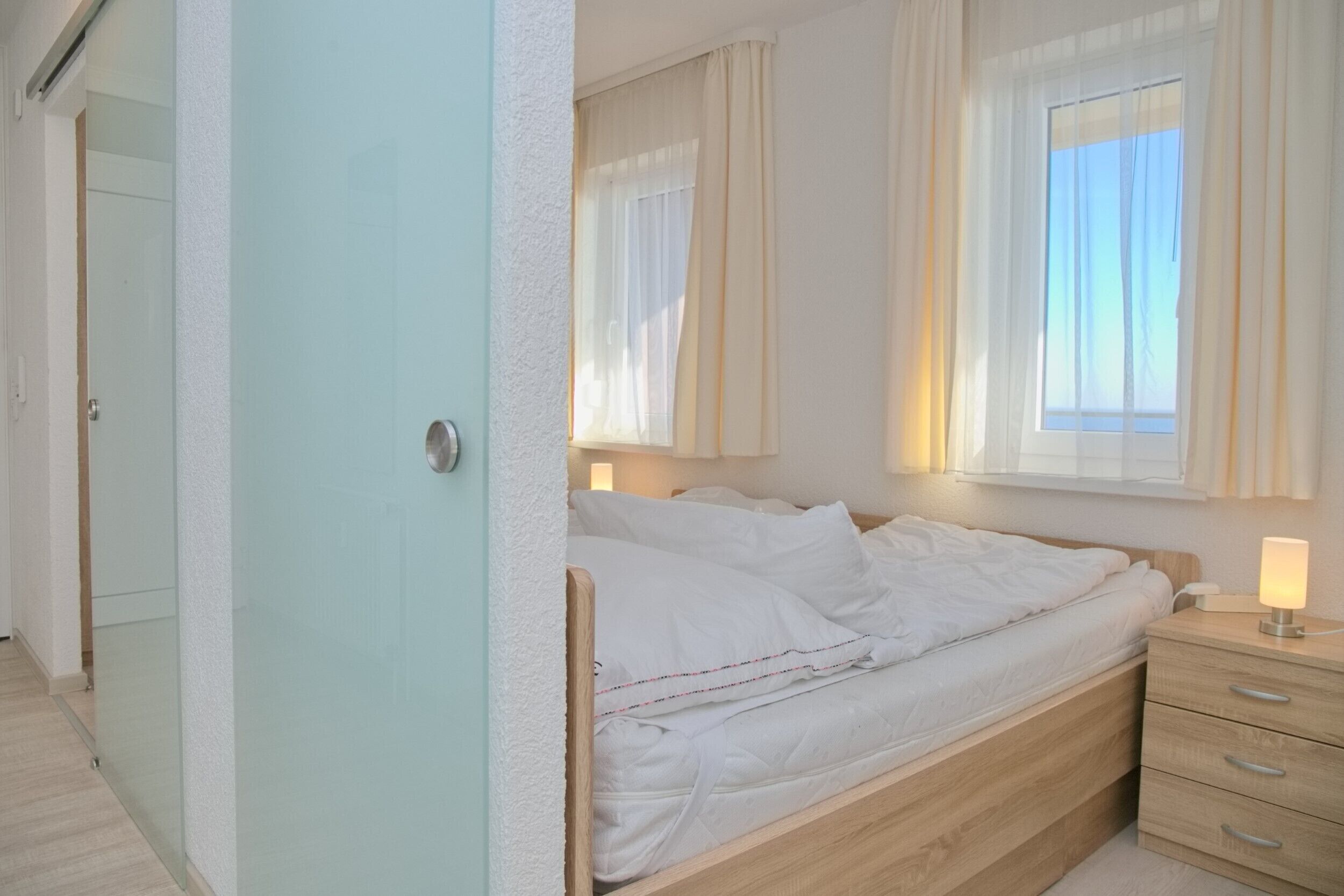Une chambre à coucher avec un lit, une table de chevet et une fenêtre avec des rideaux.