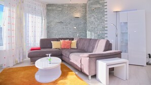 A modern living room with a sectional sofa, a white coffee table, and a small white side table.