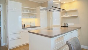 A modern kitchen with white cabinetry, a central island, and built-in shelves.