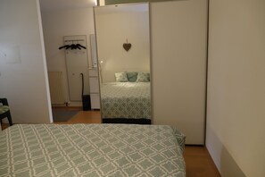A bedroom with a bed, a wardrobe, a radiator, and a hanging coat rack. - Fürstenhof Appartement 3 (Grömitz)