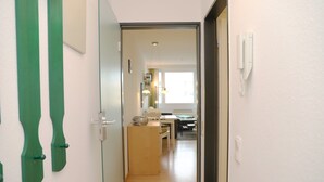 A narrow hallway leading to a dining area with a wooden table and chairs, a small kitchen area with a refrigerator and a sink, and a window providing natural light. - Tannenburg App. 504 Inkl. Wlan (Grömitz)