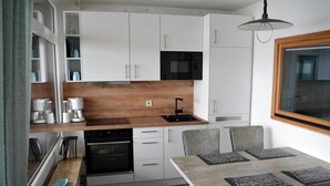 Una cocina moderna con armarios blancos, encimera de madera, horno empotrado y comedor con mesa y sillas.