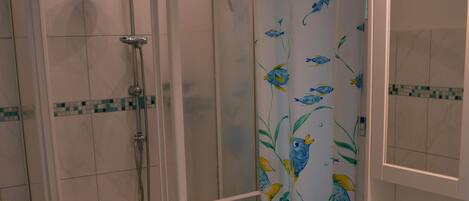 A bathroom with a shower, toilet, sink, and a small stool.