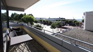 En balkon med udendørs møbler og udsigt til en parkeringsplads samt bygninger i baggrunden.
