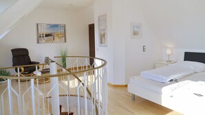 A bedroom with a bed, a chair, a desk, and a staircase. - House Deichgraf Whg. 12 (Grömitz)