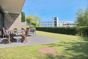 Une terrasse extérieure avec une table et des chaises, un couvercle de regard d’égout et un bâtiment en arrière-plan.