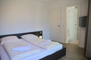 Un lit double avec une tête de lit sombre, dans une chambre d’hôtel.