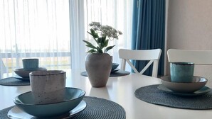 A dining table with blue ceramic bowls and plates, a potted plant, and a white chair. - Haus Baltic App. 188 Inkl. Wlan (Grömitz)