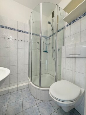 A bathroom with a glass-enclosed shower, a toilet, and a sink.