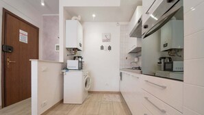 Una cocina compacta con armarios blancos, lavadora integrada y microondas.
