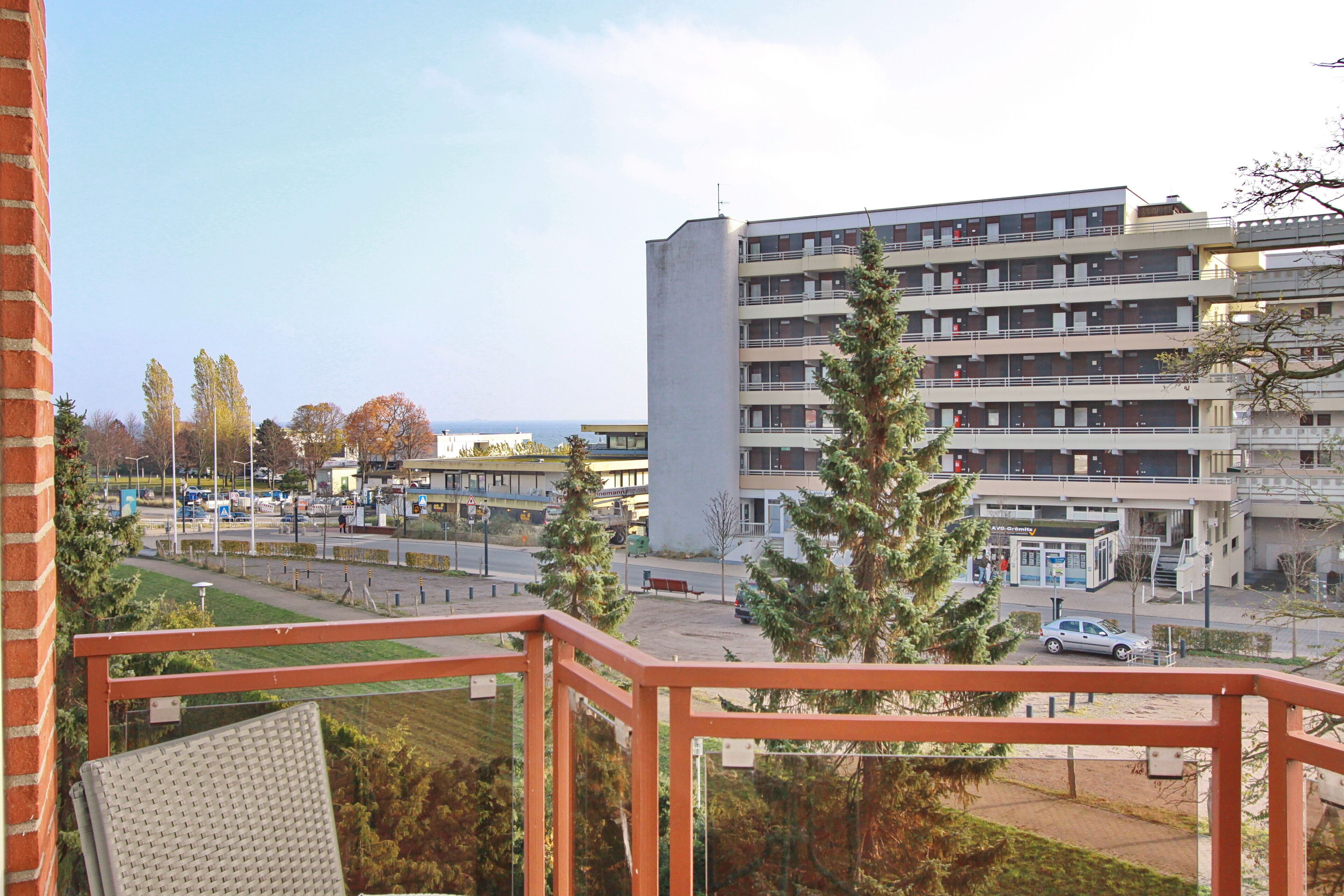 A multi-story building with a flat roof, a central courtyard, and a parking area.