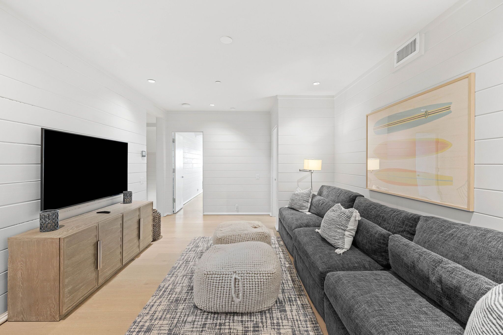 A modern living room with a flat-screen TV, grey sofa, and a wooden cabinet.